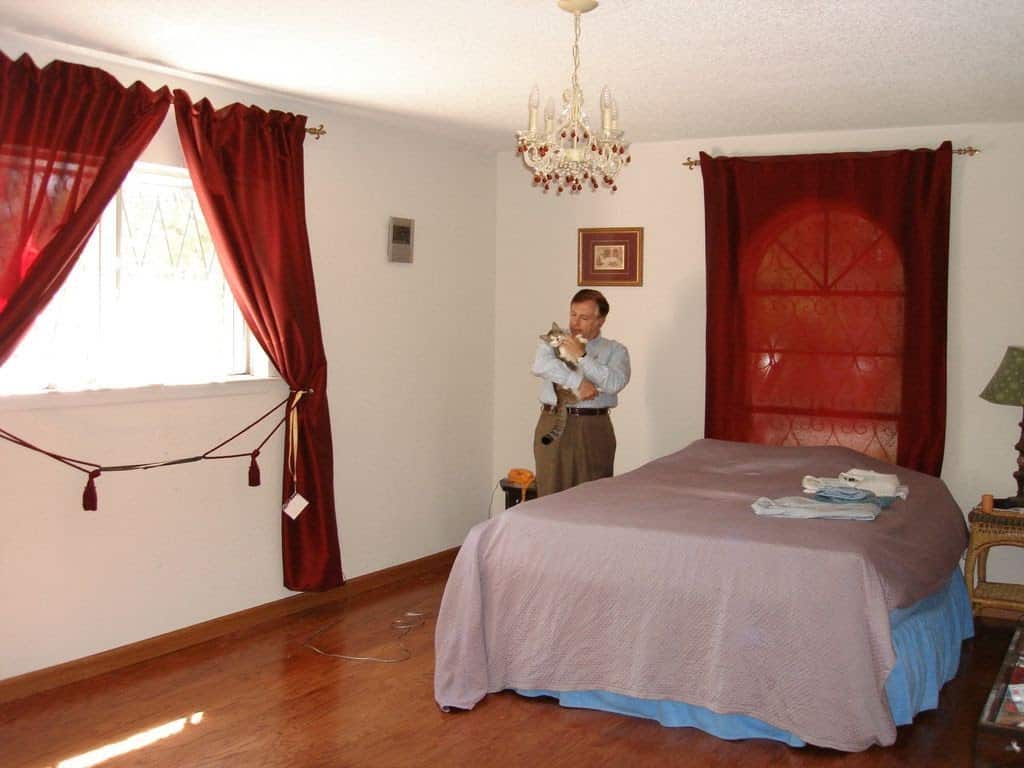 Man holding a cat in the bedroom