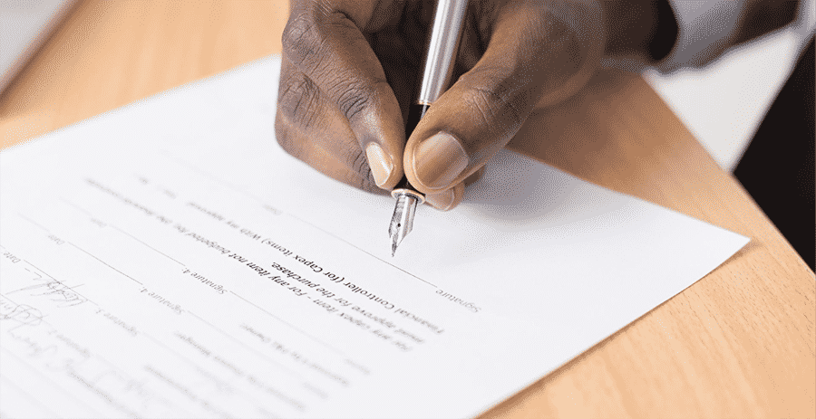man's hand signing a document