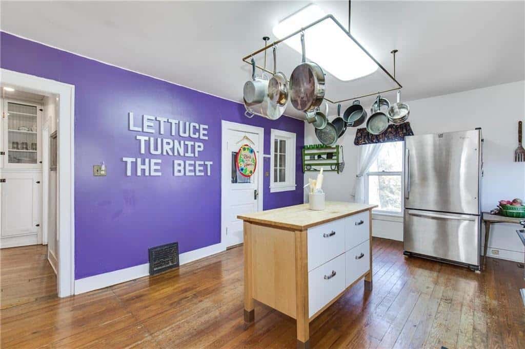 listing photo of a purple kitchen with words on the wall that read lettuce, turnip, the beet. Ha.