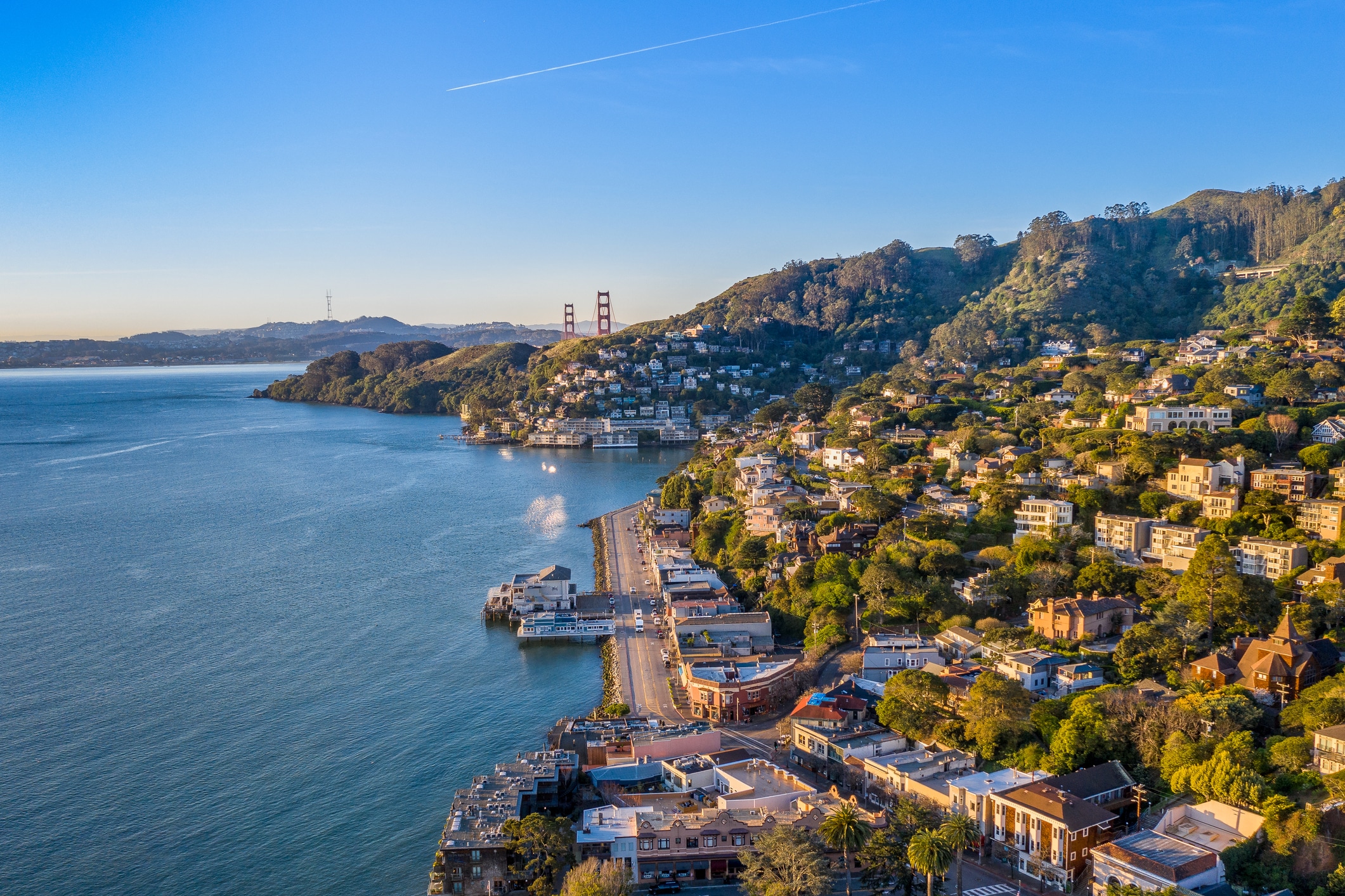 An aerial view of Sausalito on a golden morning with the Golden Gate Bridge peaking over the hillside.