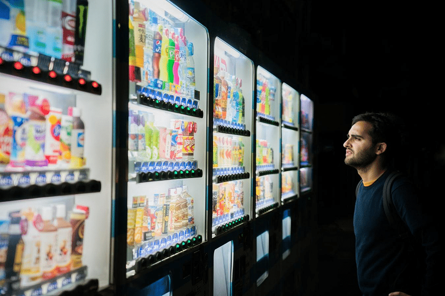 Young man choosing a drink from vending machines