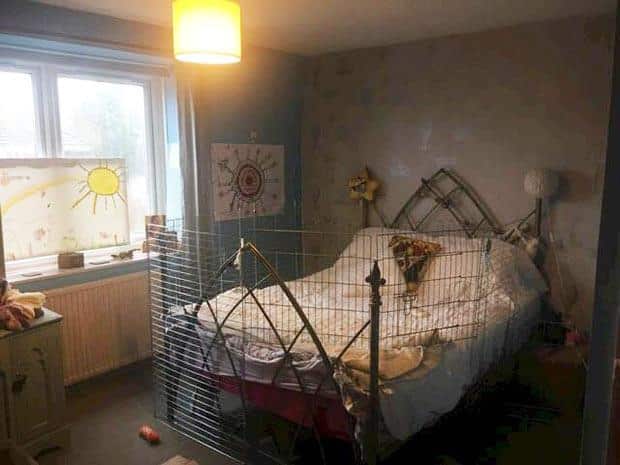 A bedroom with a bed covered in chicken wire
