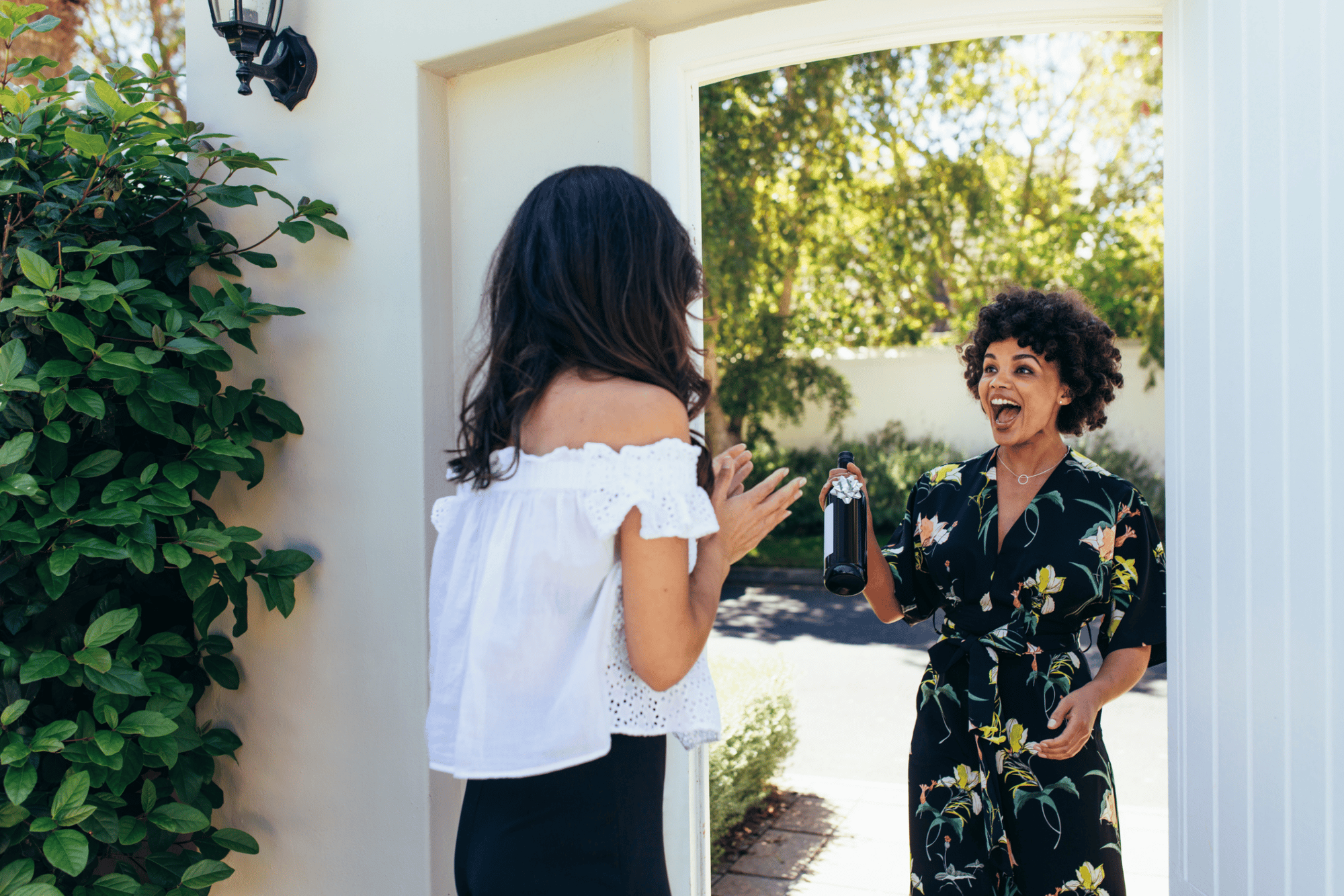 Photos of a real estate agent bringing the gift of a bottle of wine to her client as a closing gift at the front door of her client's new home