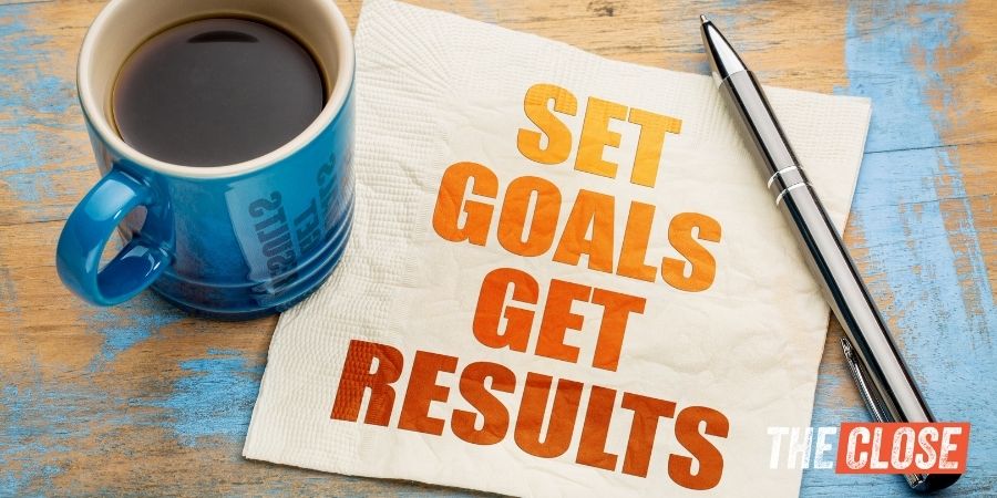 wooden table with coffee cup, pen, and paper napkin with "set goals get results" spelled out