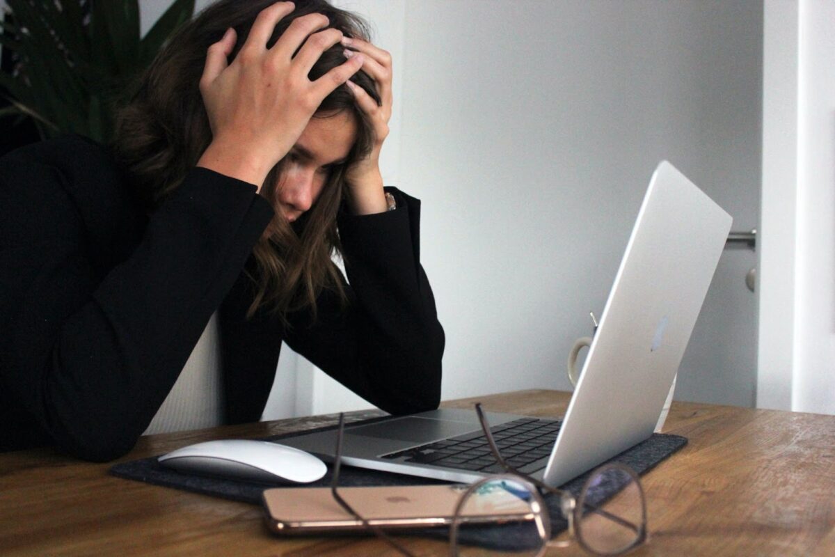 Real estate agent frustrated in front of laptop with hands on her head