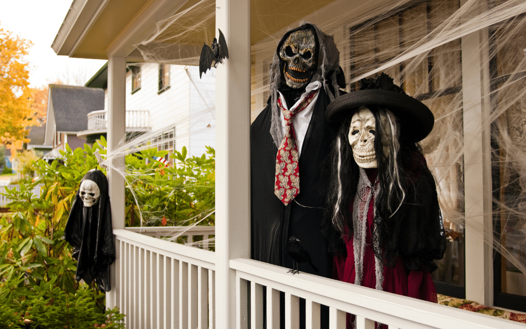 House front porch decorated for Halloween with hanging apparitions and cobwebs