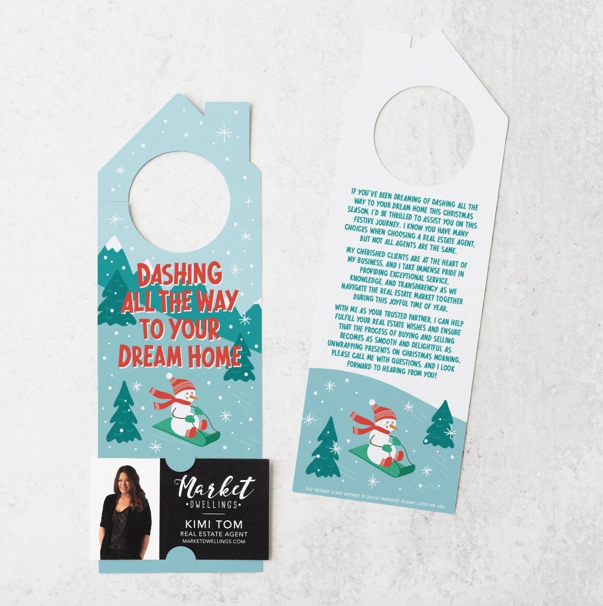 House shaped door hanger with colorful holiday image on front and back of snowman on a sled, with "Dashing all the way to your dream home" printed on the front.