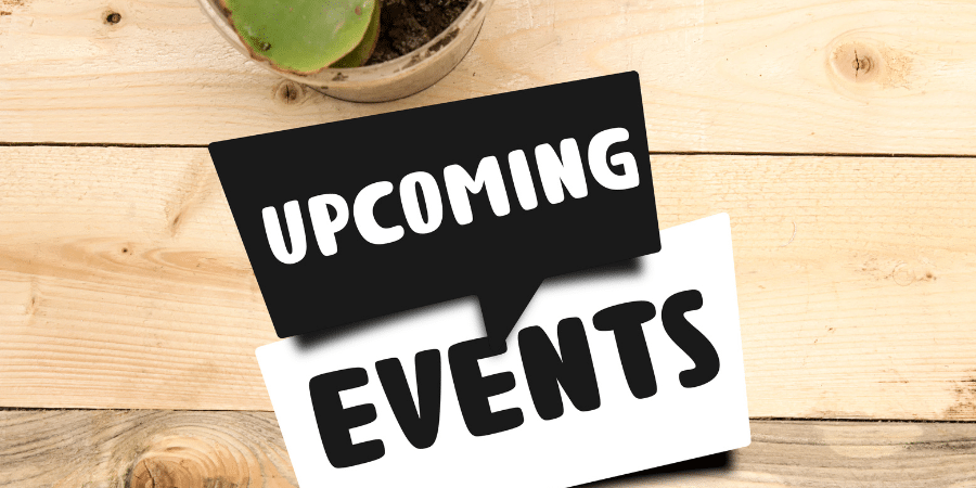 Two small signs that read, "Upcoming" and "Events" lying on a wooden table top.