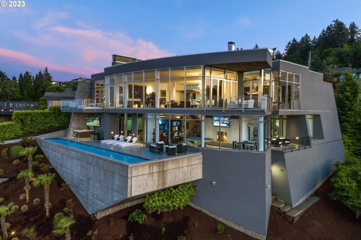 A gray post-modern house with a pool and glass windows