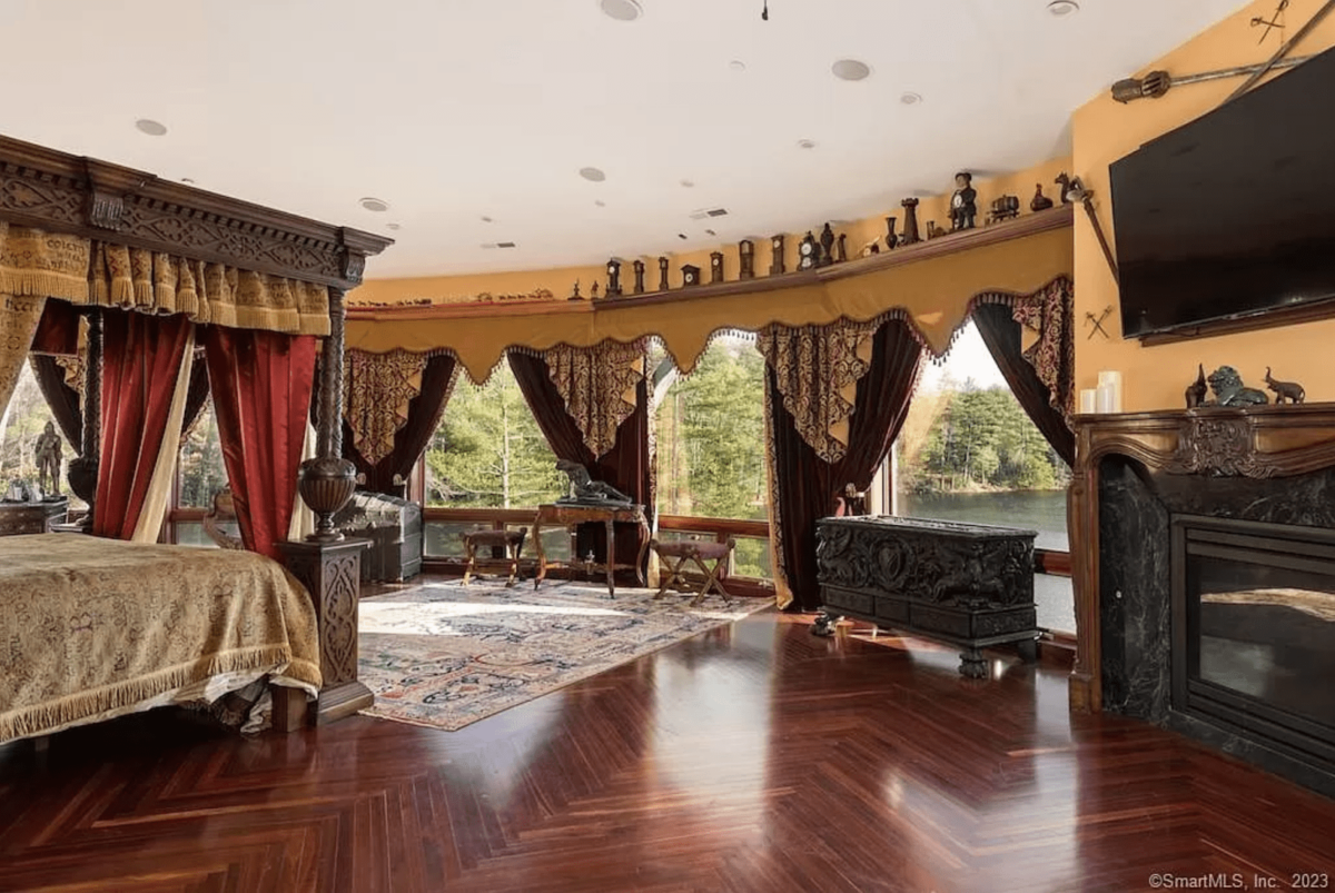 A room with a four-poster bed and windows overlooking the lake