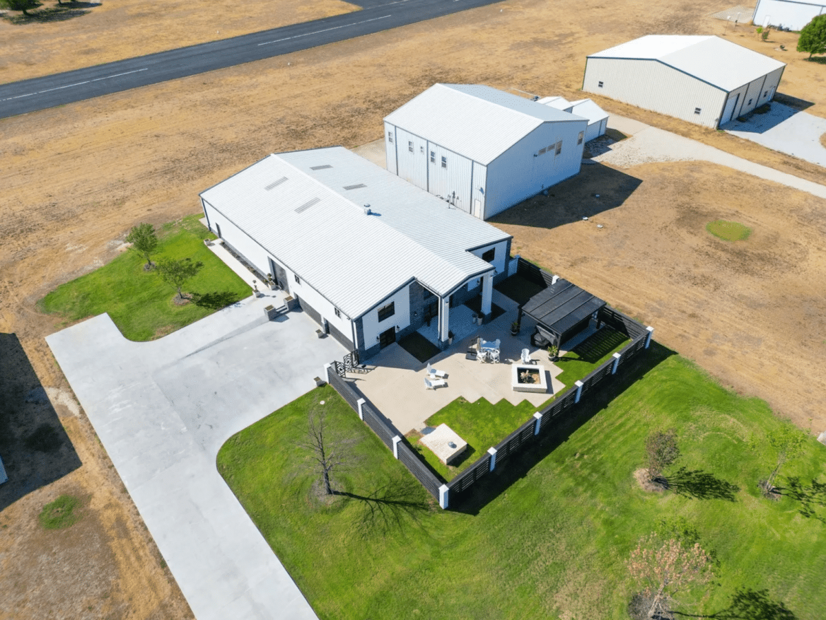 Aerial view of a huge house with a hangar and runway