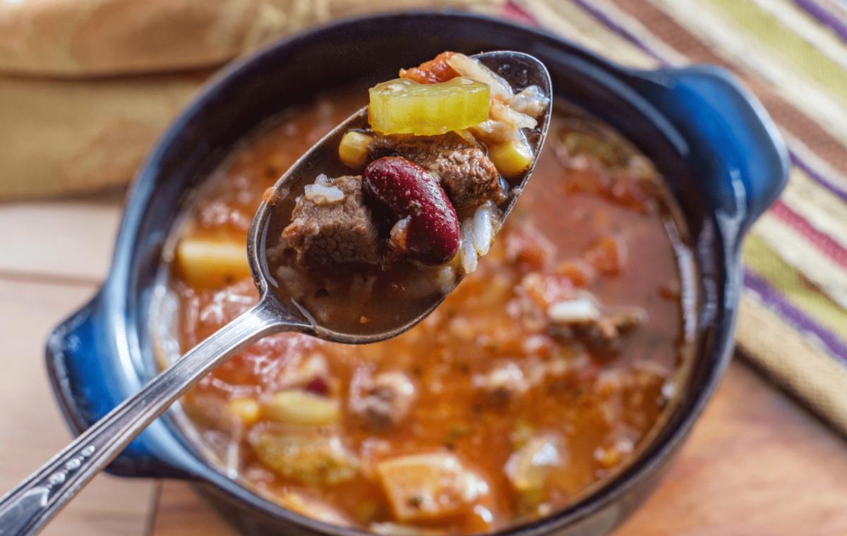 Slow cooker with a close up of a spoonful of stew