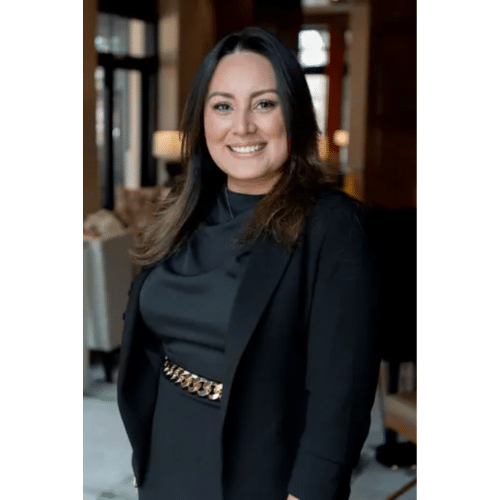 A real estate agent wearing a black dress, black blazer, and chain belt