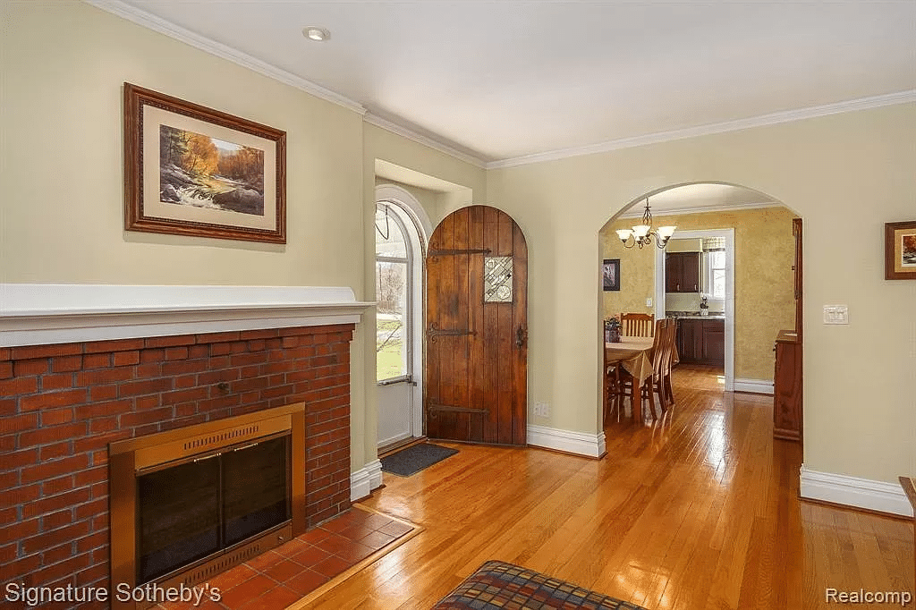 A home's arched door, fireplace, and an archway that shows a glimpse of the dining area